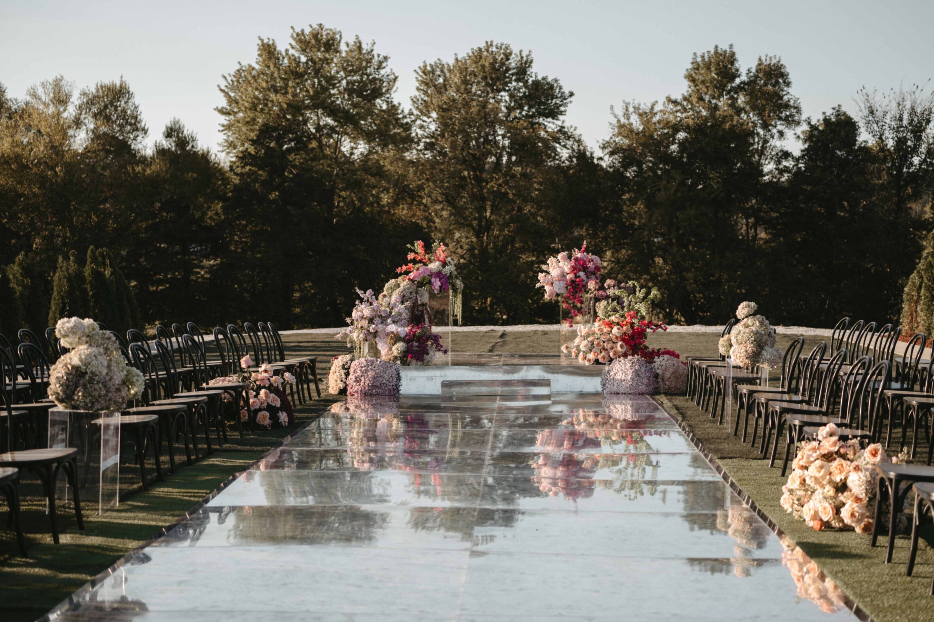 Elegant outdoor wedding table setup with floral centerpieces and string lights.