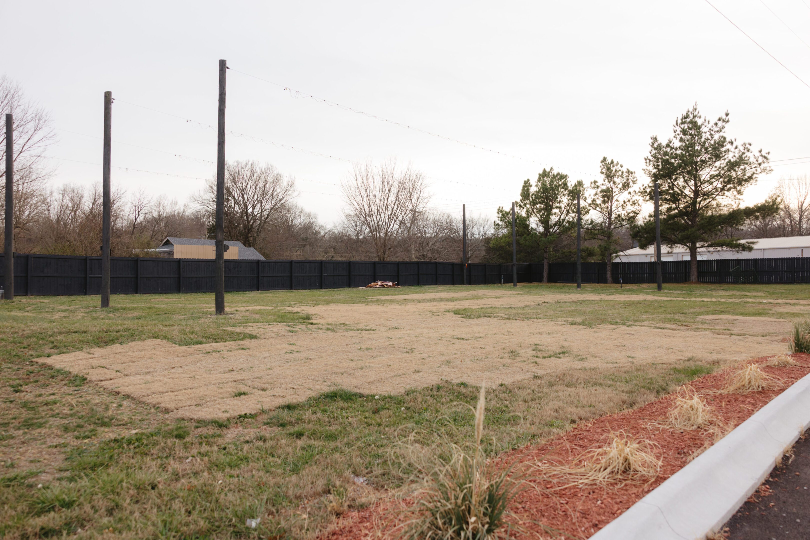 Empty outdoor volleyball court with a net and surrounding trees.