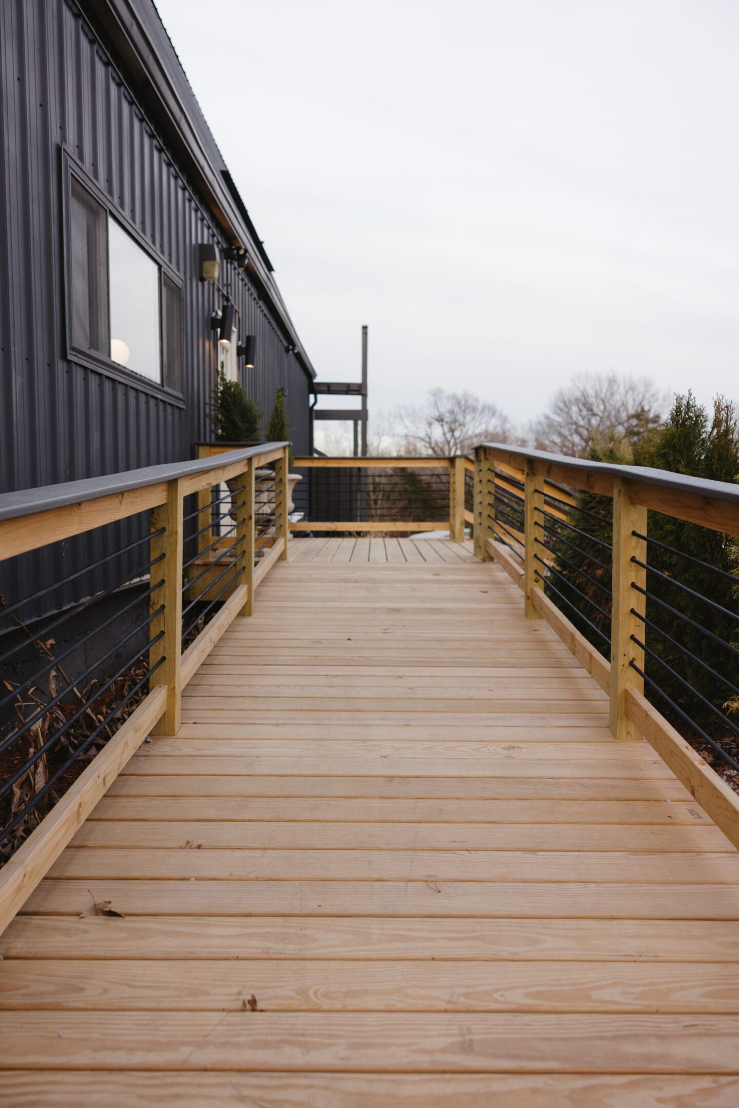 Wooden deck with cable railing extending from a modern building.