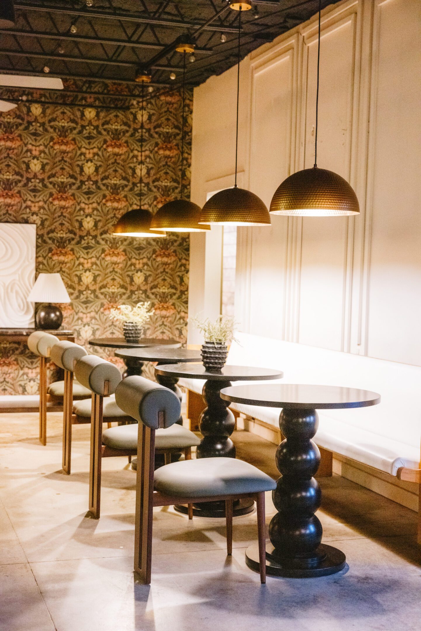 Cozy dining area with round tables and cushioned chairs under warm pendant lights.