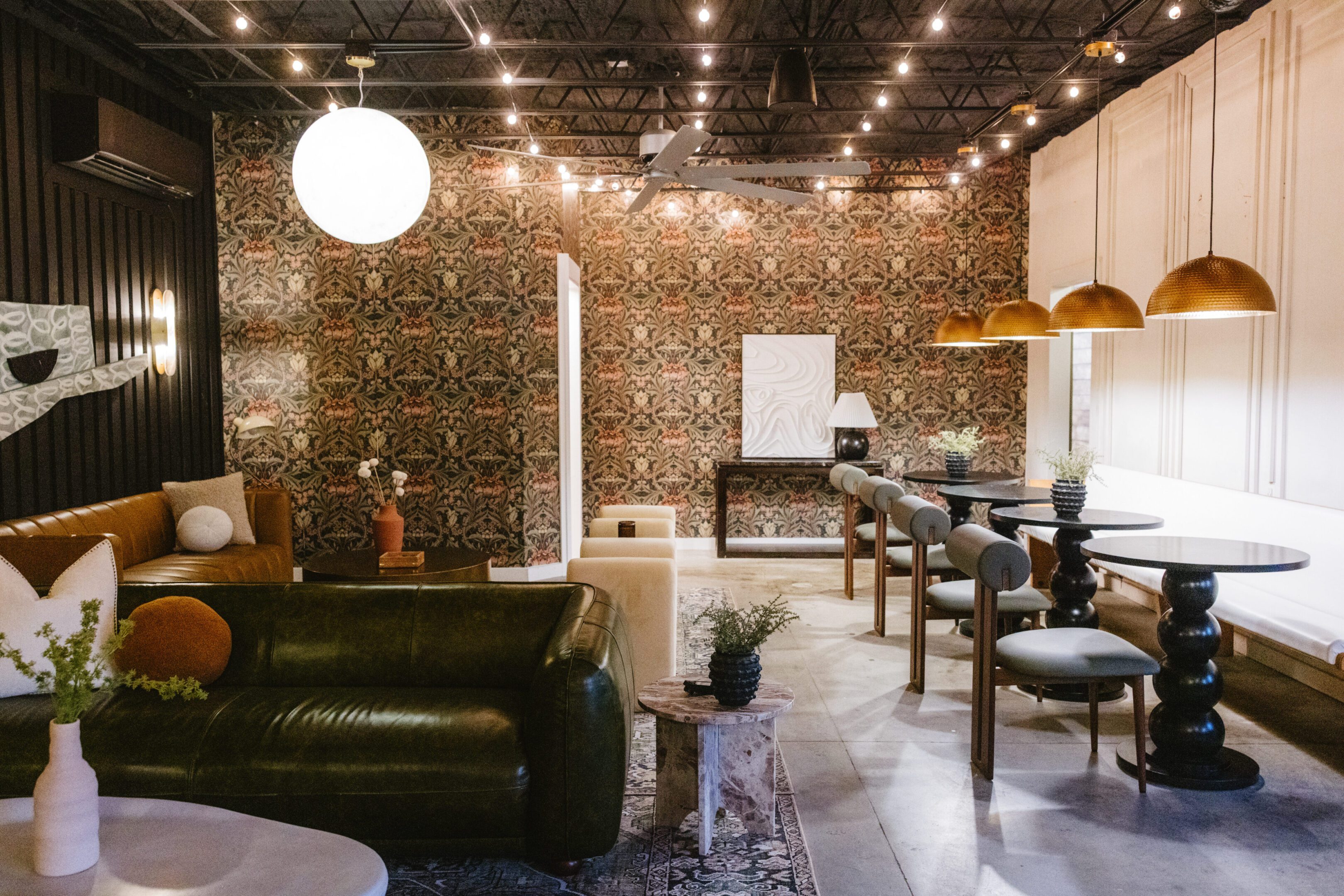 Cozy cafe interior with string lights and patterned wallpaper.