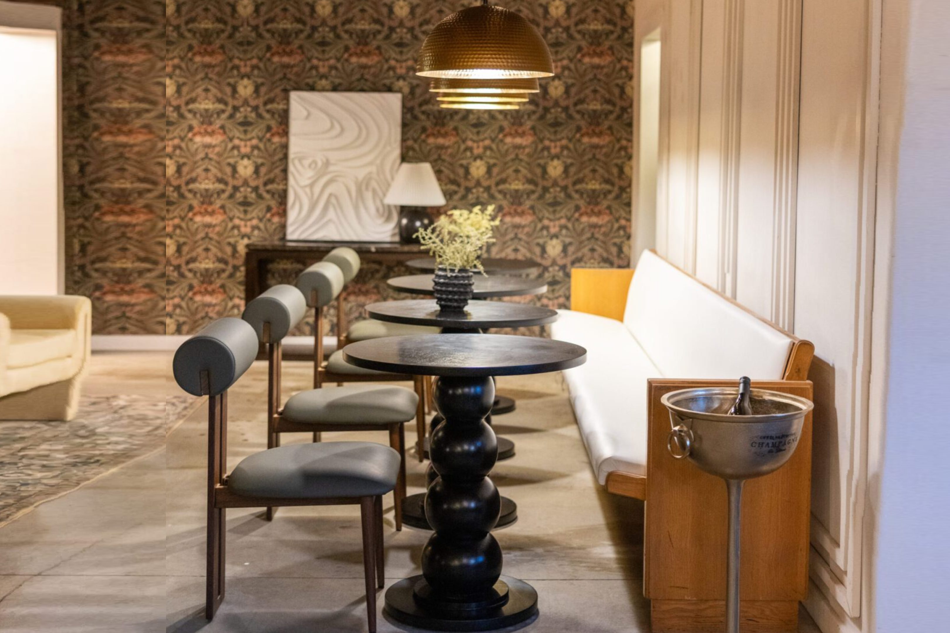 Elegant dining area with round tables and cushioned chairs against a patterned wall.
