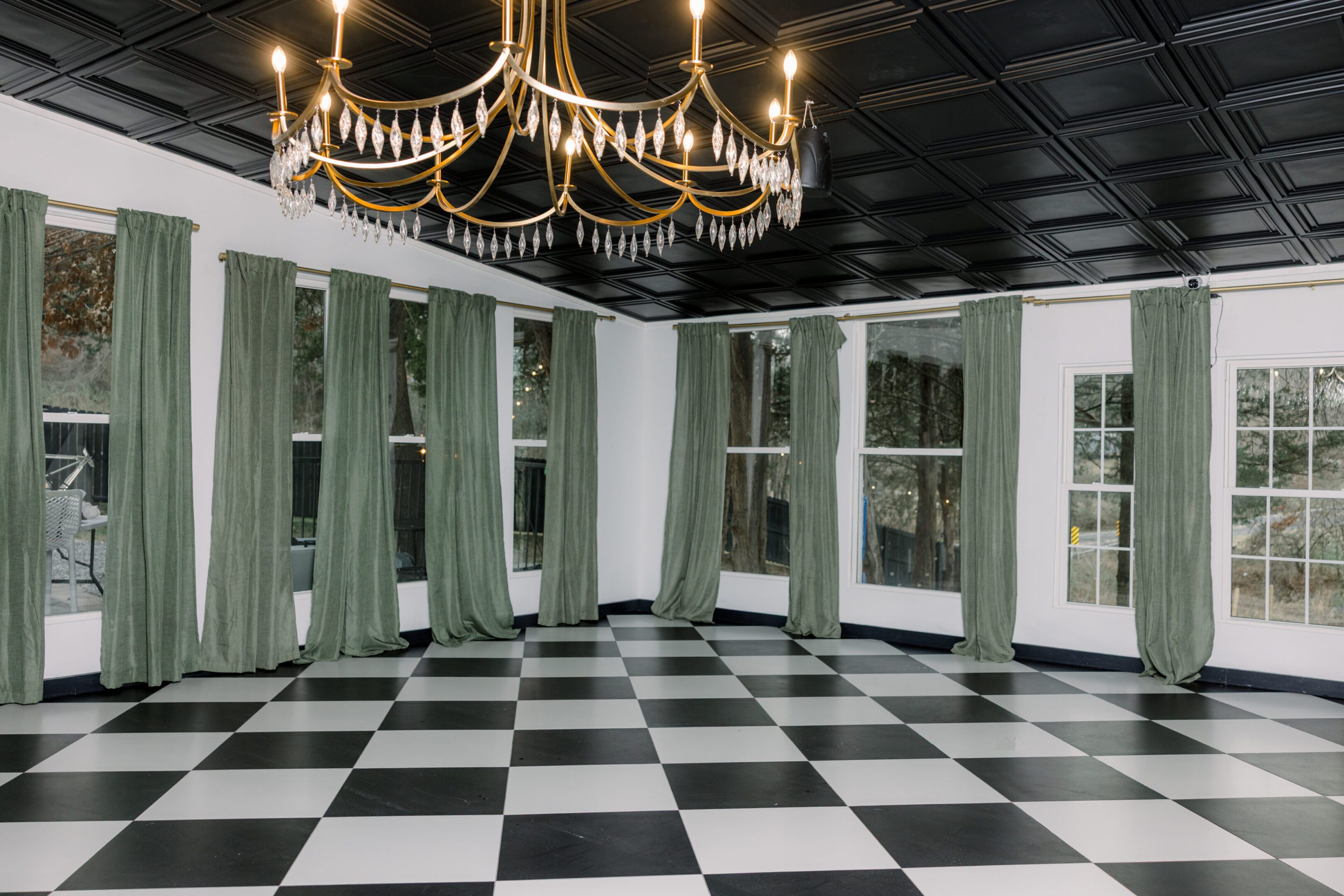 Elegant room with black-and-white checkered floor and green curtains.