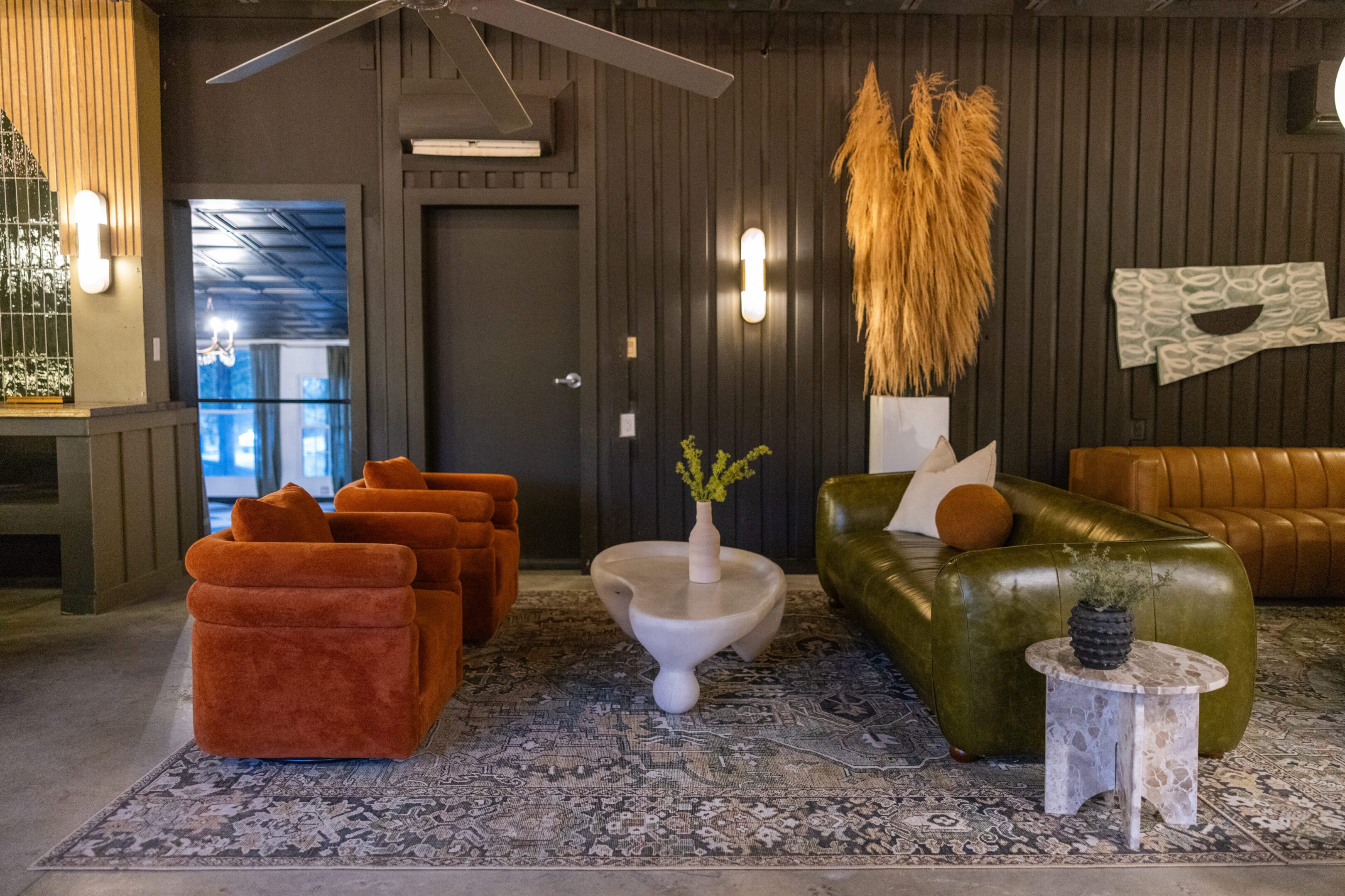 Cozy living room with velvet chairs and rustic wooden walls.