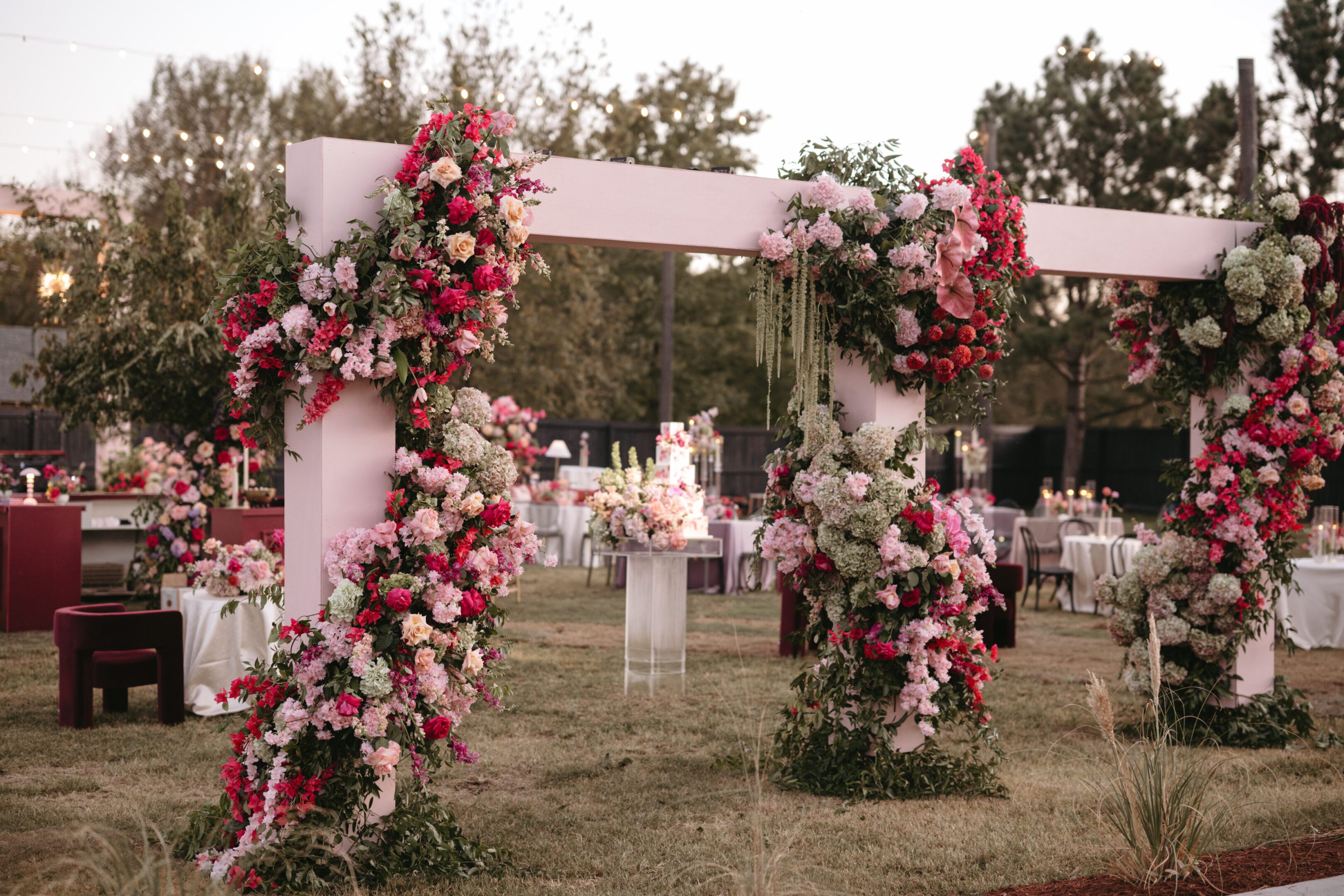 Elegant floral wedding arch with pink and white flowers in an outdoor garden.