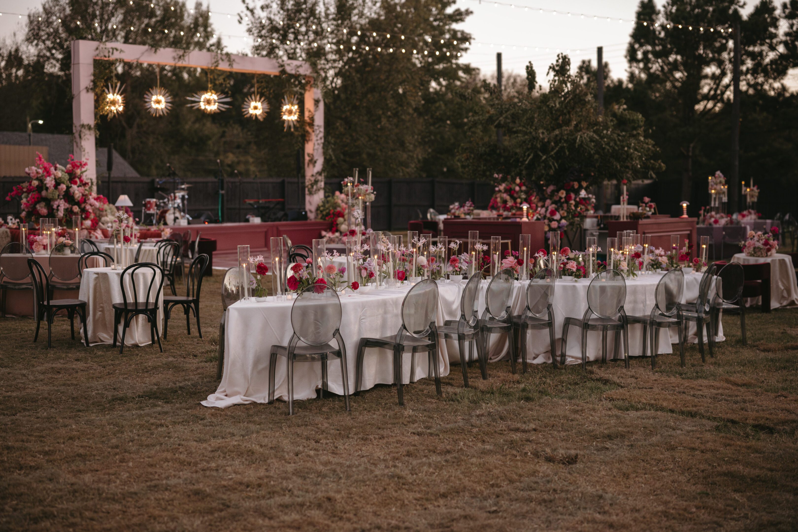 Outdoor wedding reception with elegant table settings and string lights.