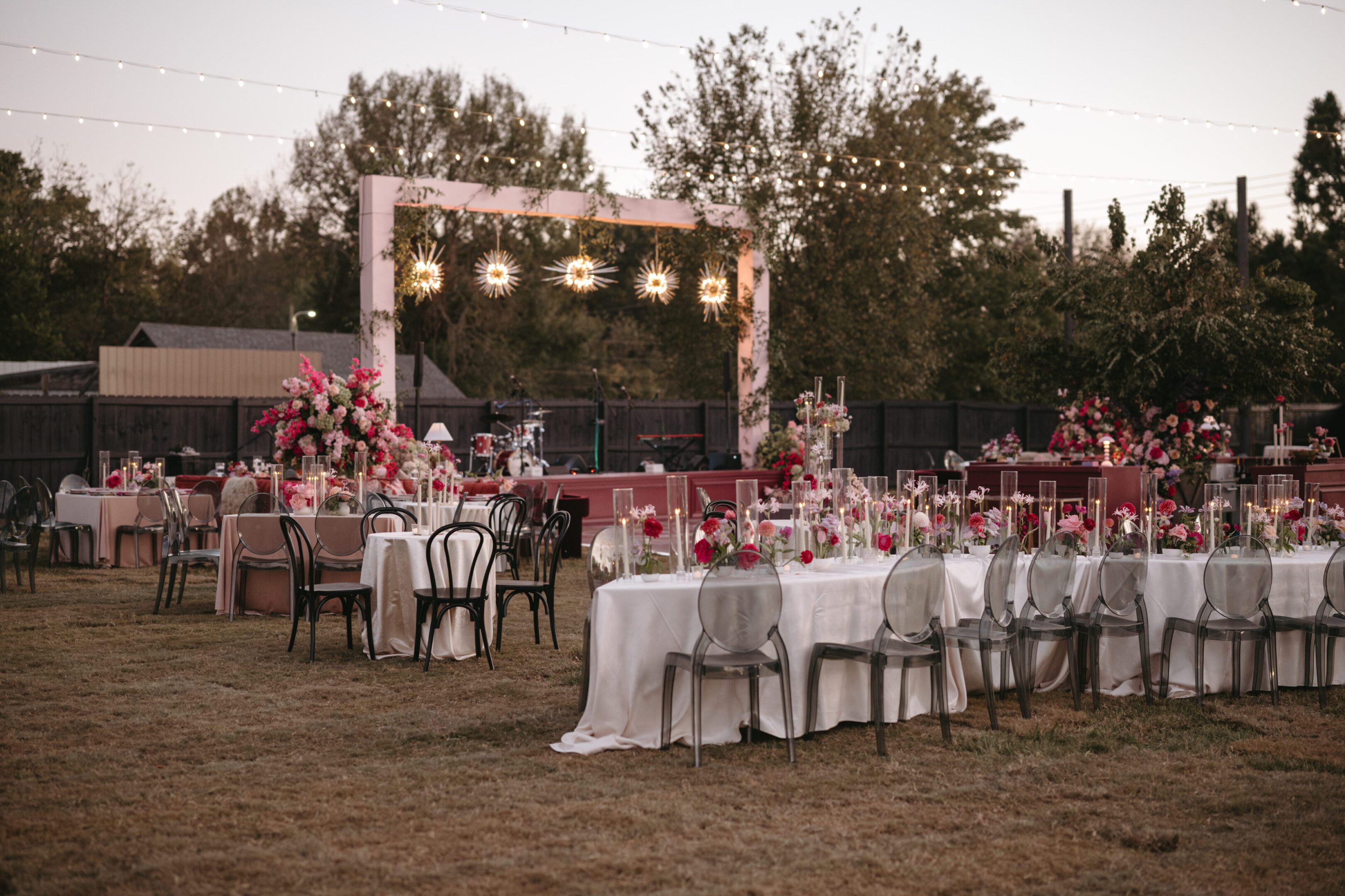 Elegant outdoor wedding reception setup with floral decorations and string lights.
