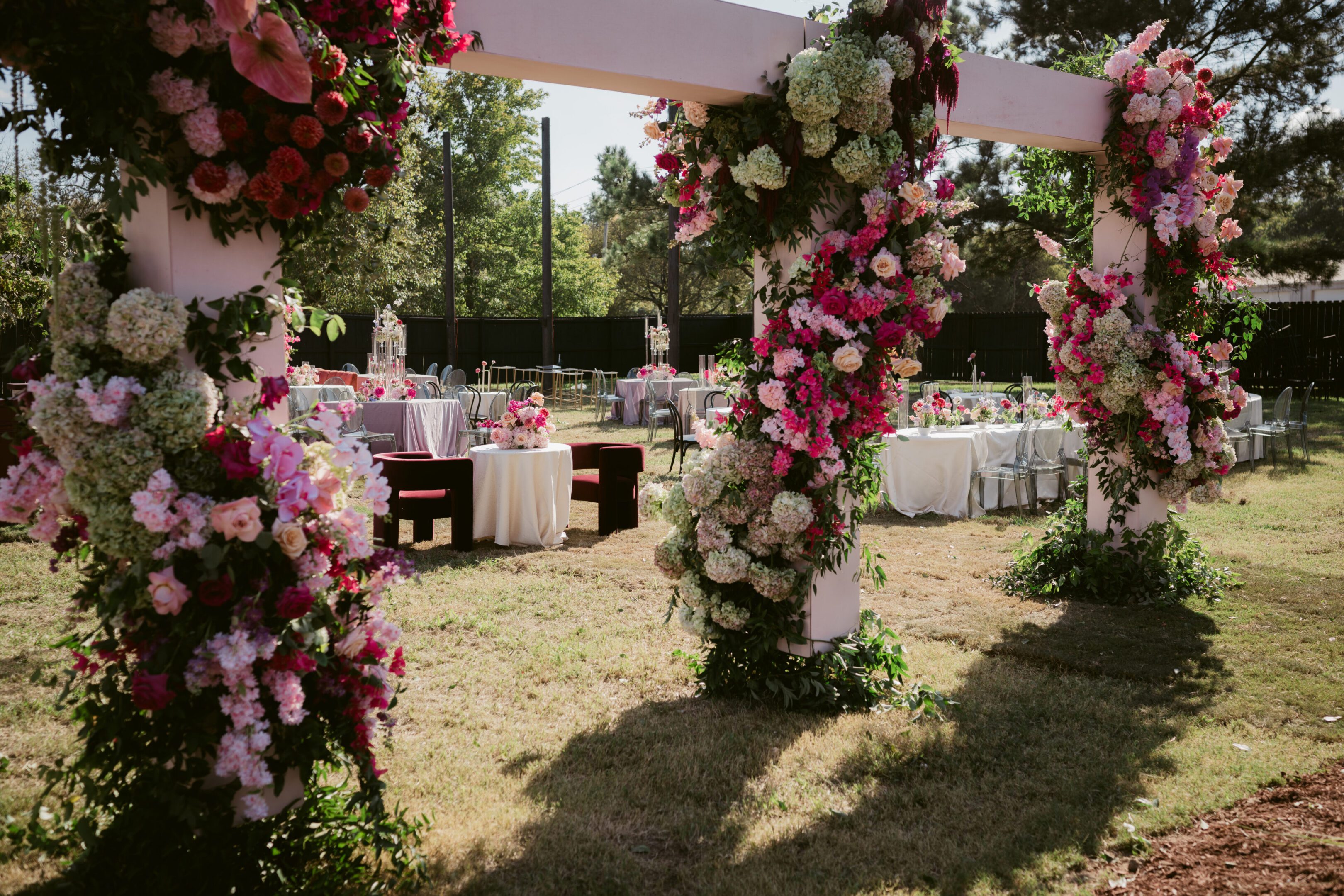 Outdoor wedding ceremony with floral arch and decorated tables.