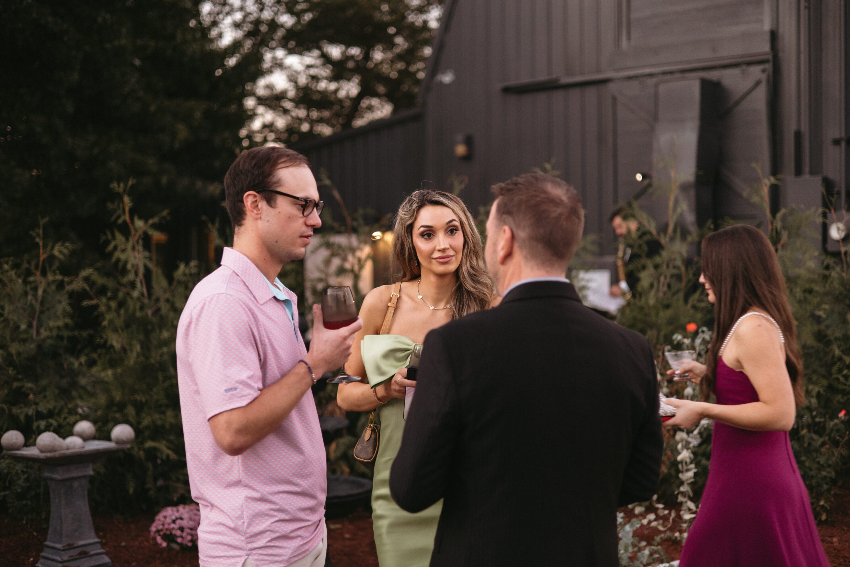 Three people enjoying drinks and conversation outdoors at a social gathering.