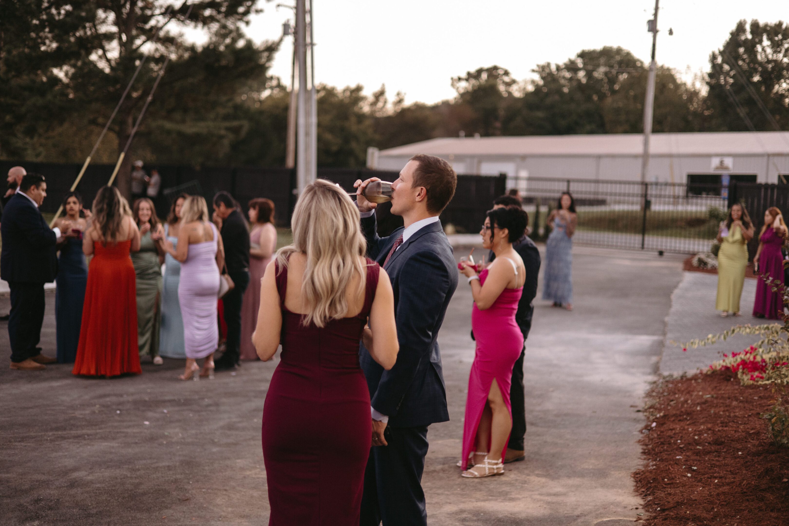 Guests socializing outdoors at a formal event during sunset.