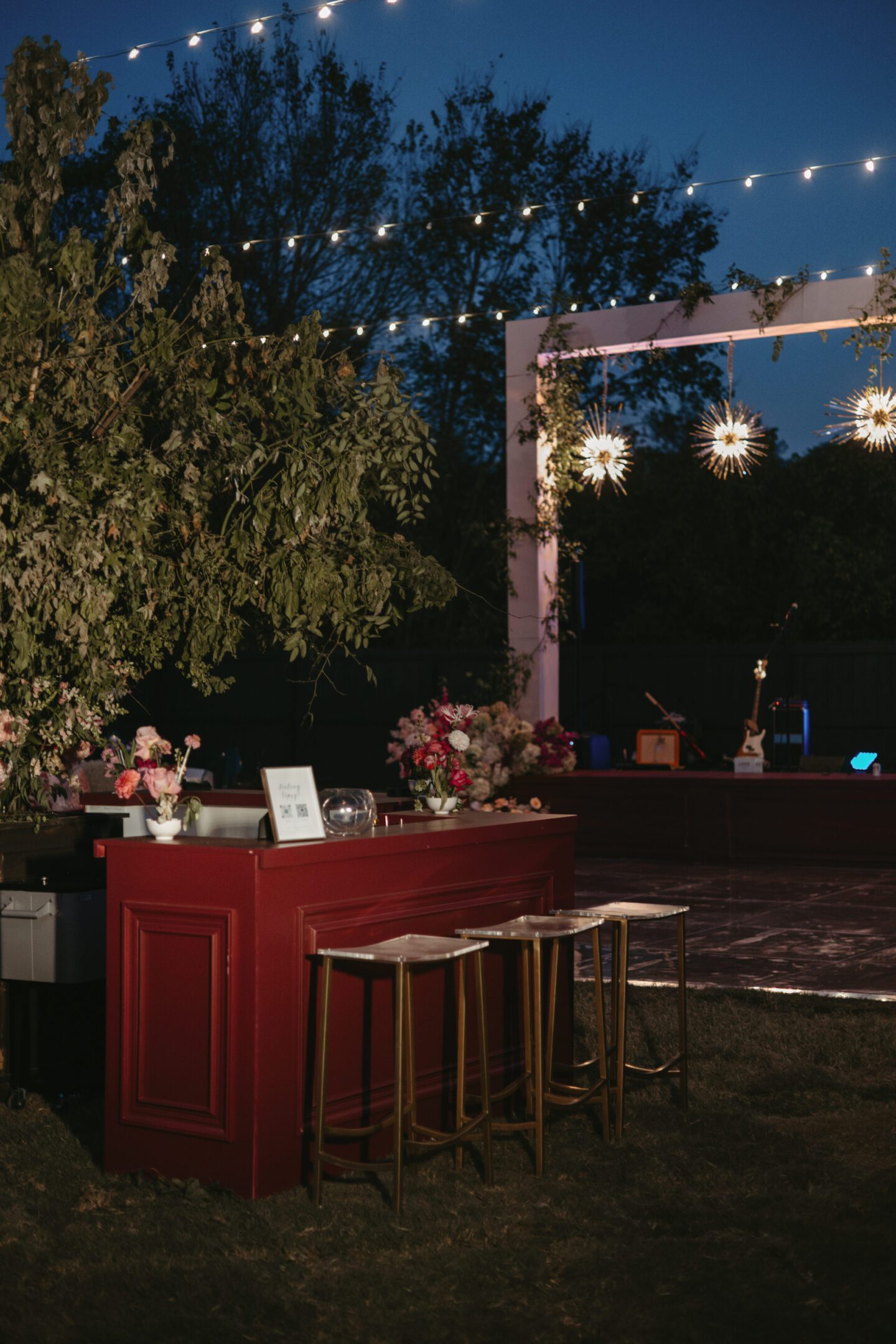 Outdoor evening bar setup with stools and warm string lights.
