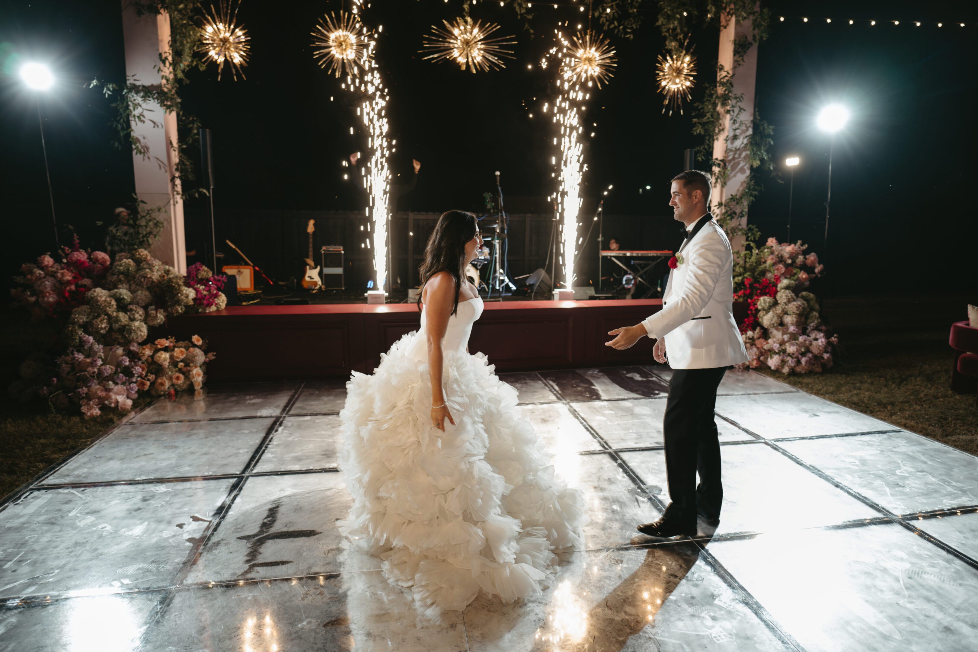 Bride and groom dancing with sparklers at night.