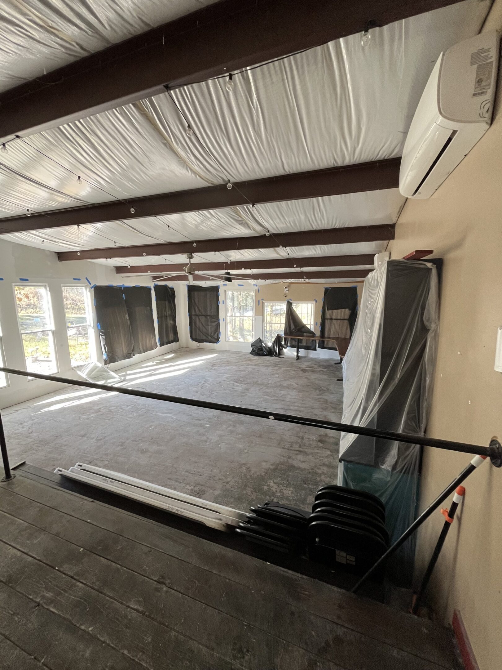 An unfinished interior space with exposed beams and construction materials.