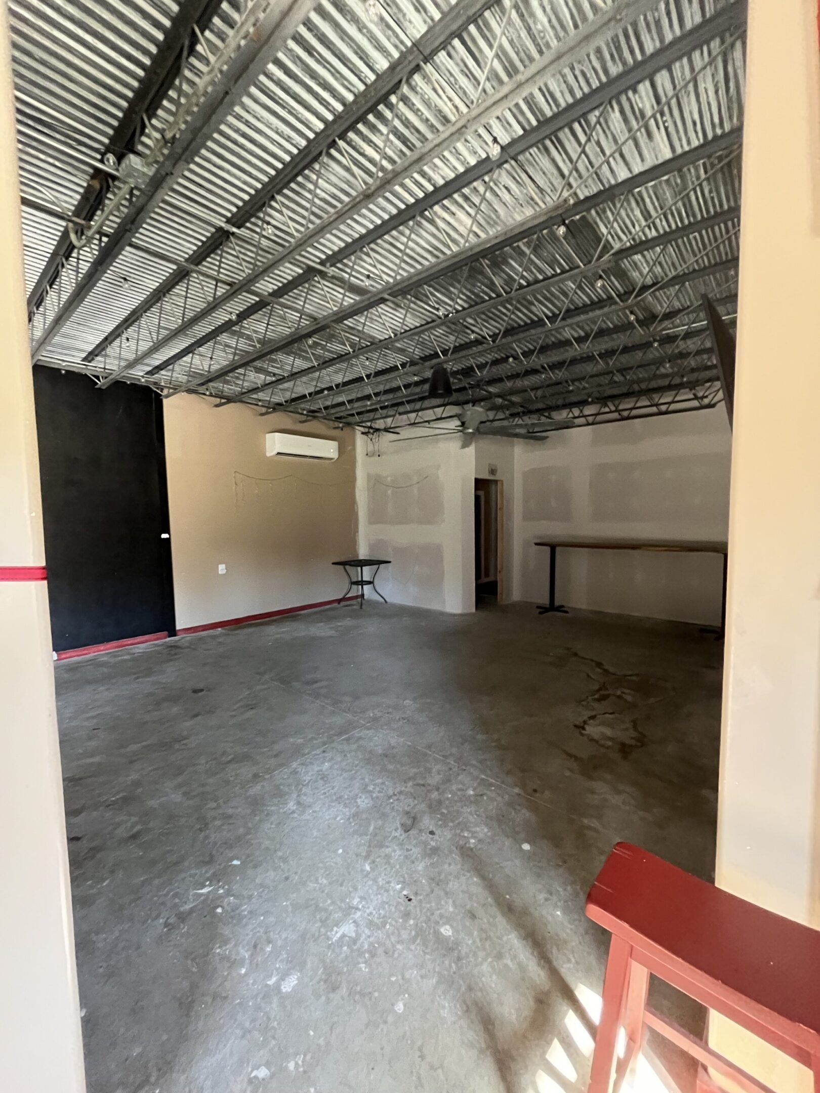 Empty commercial space with concrete floor and exposed ceiling.