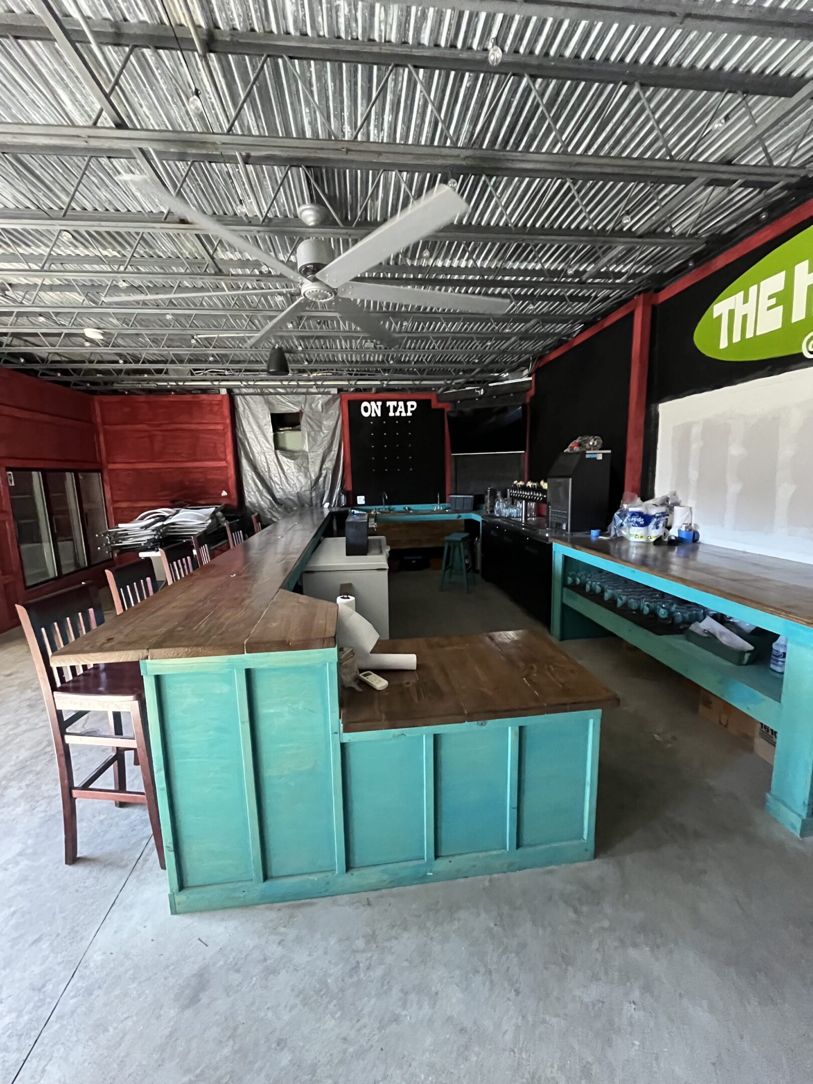 Interior of a rustic bar with wooden tables and a large screen.