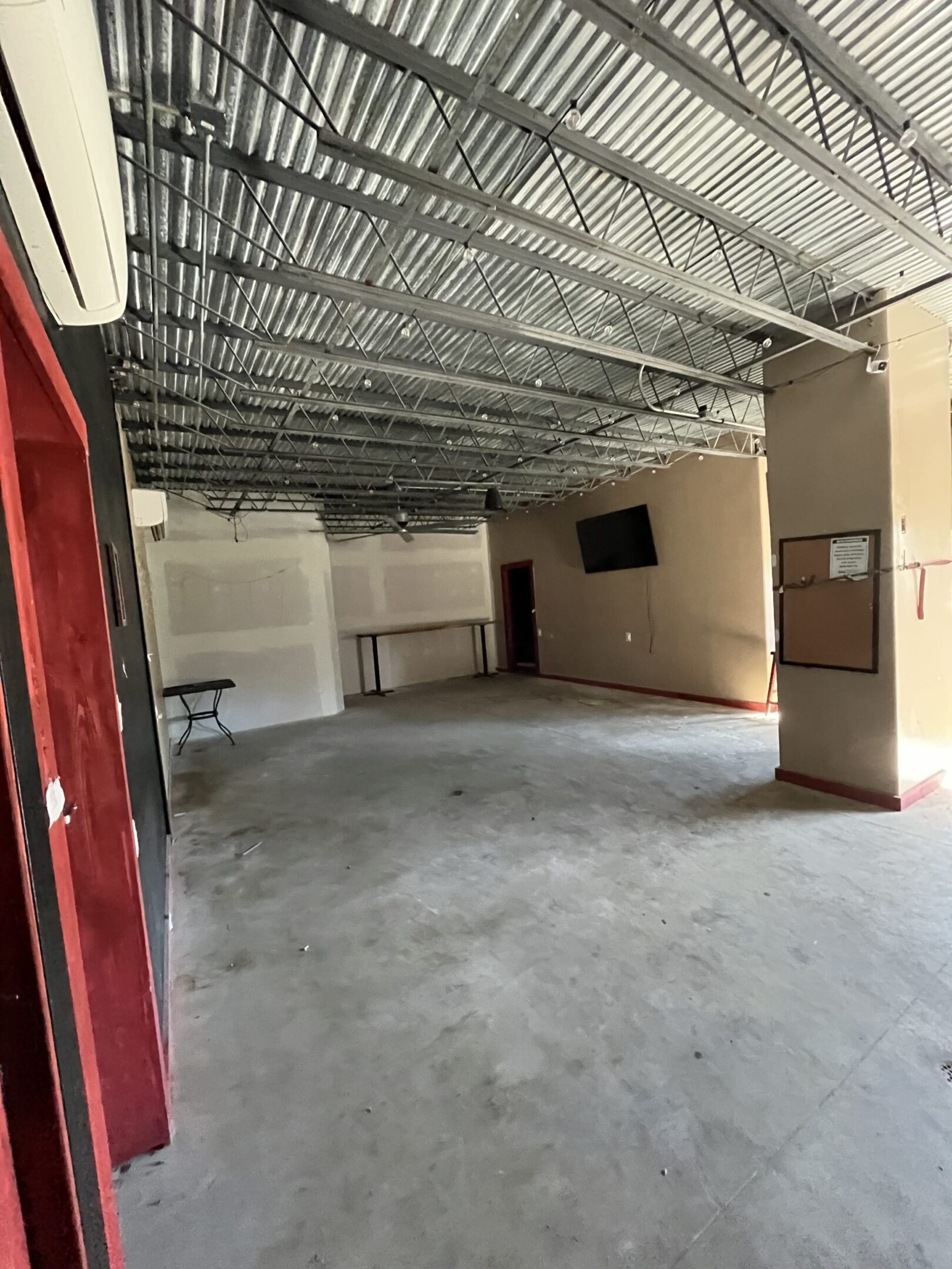 Empty commercial space with concrete floor and exposed ceiling.