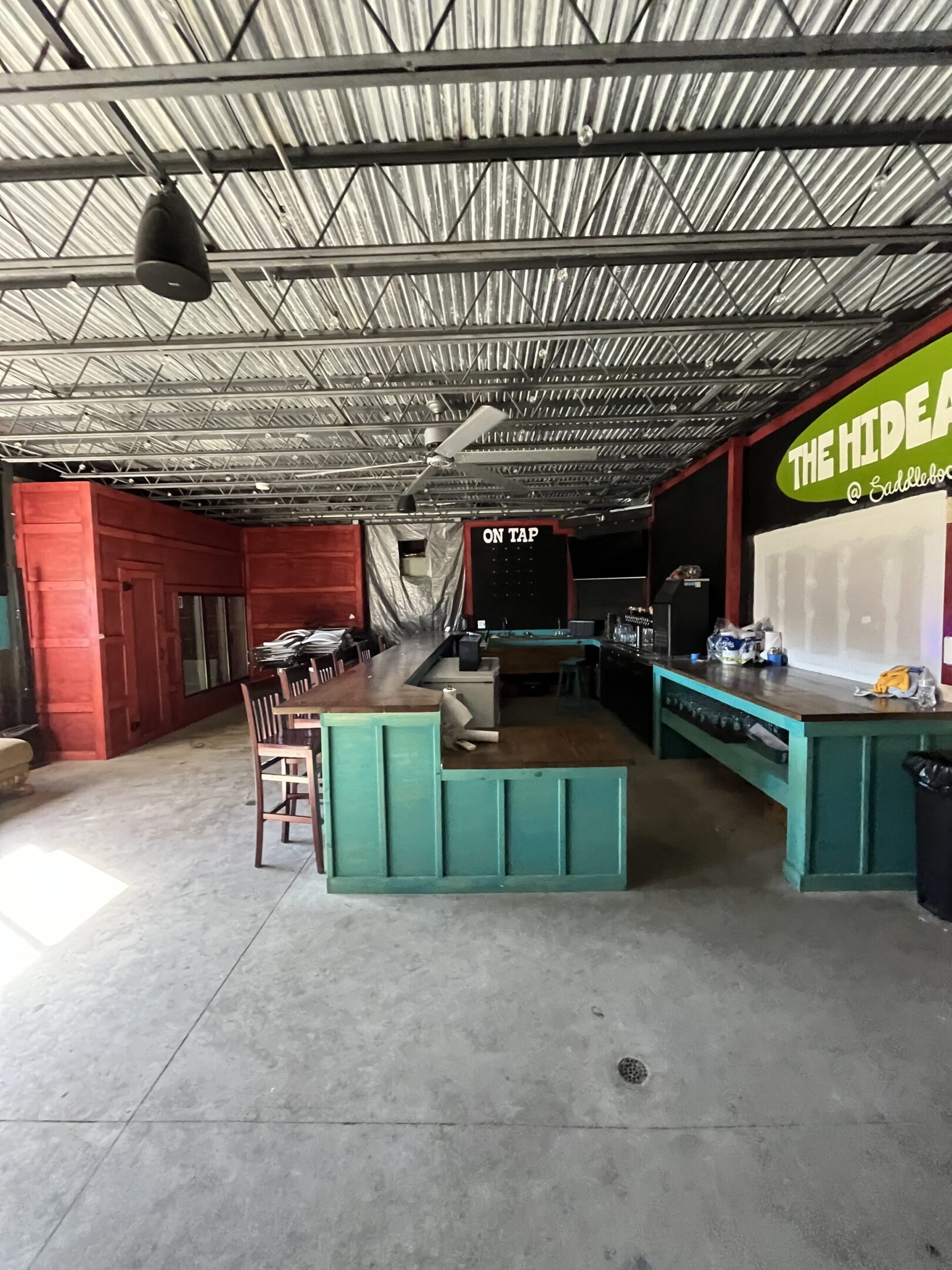 Spacious modern cafe with green seating and a vibrant red wall.