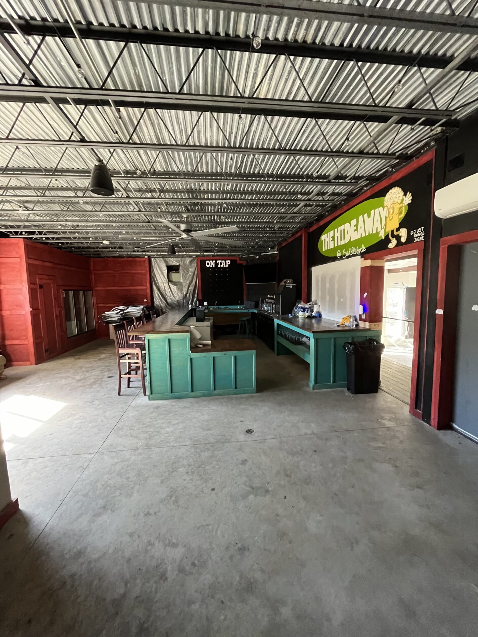 Empty indoor bar area with a turquoise counter and red walls.