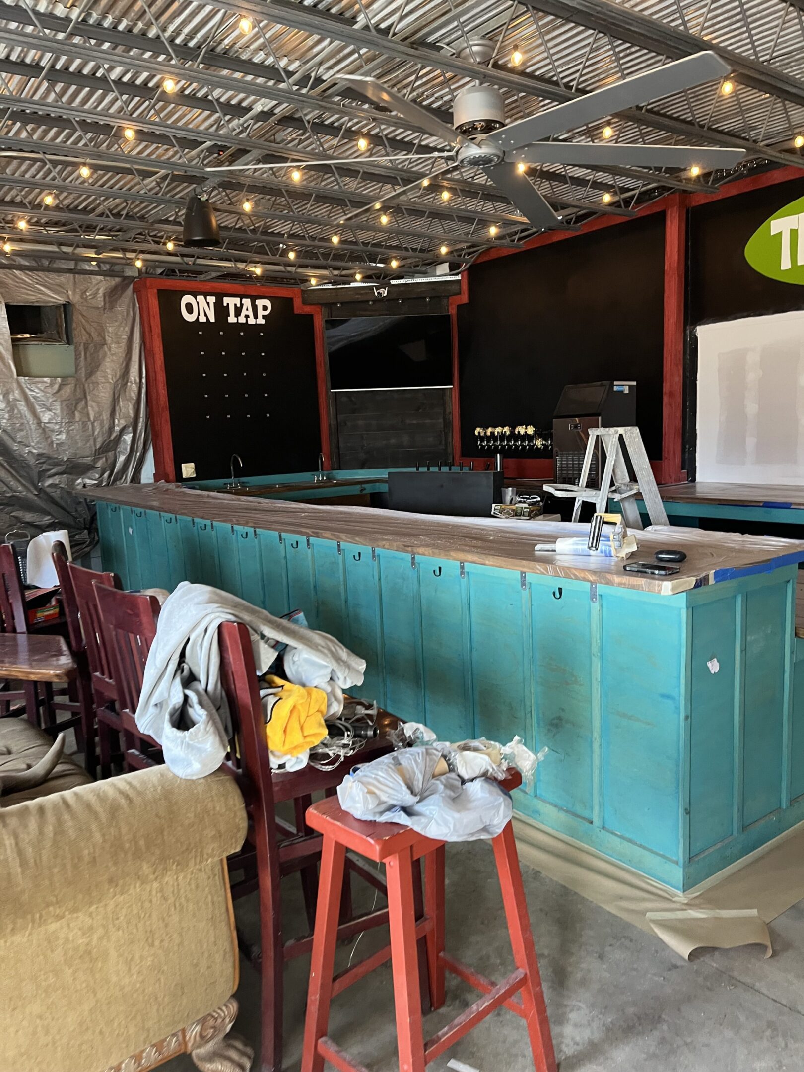 A rustic bar counter under construction with tools and chairs around.