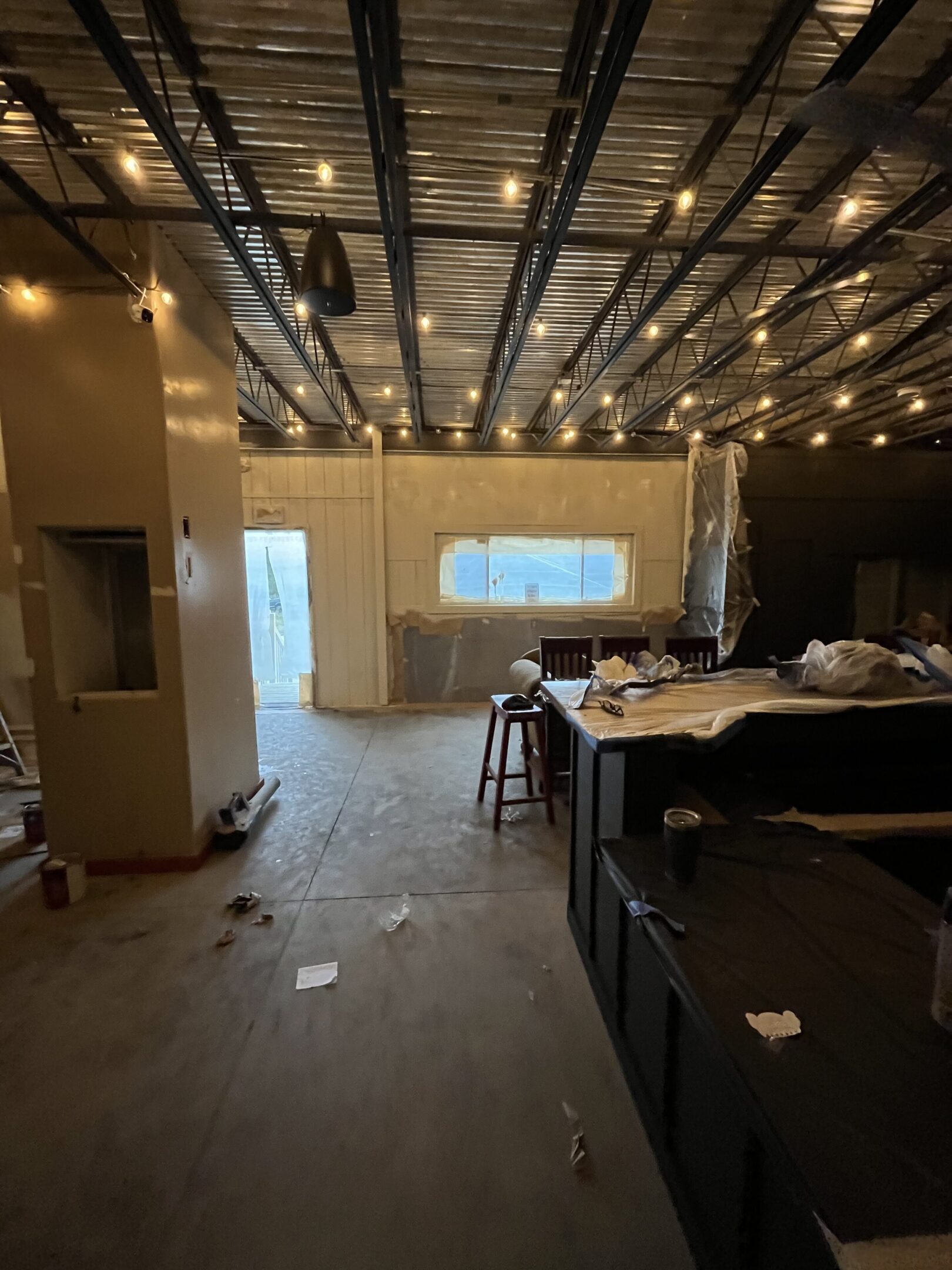 Interior of a dimly lit room under construction with scattered tools and furniture.