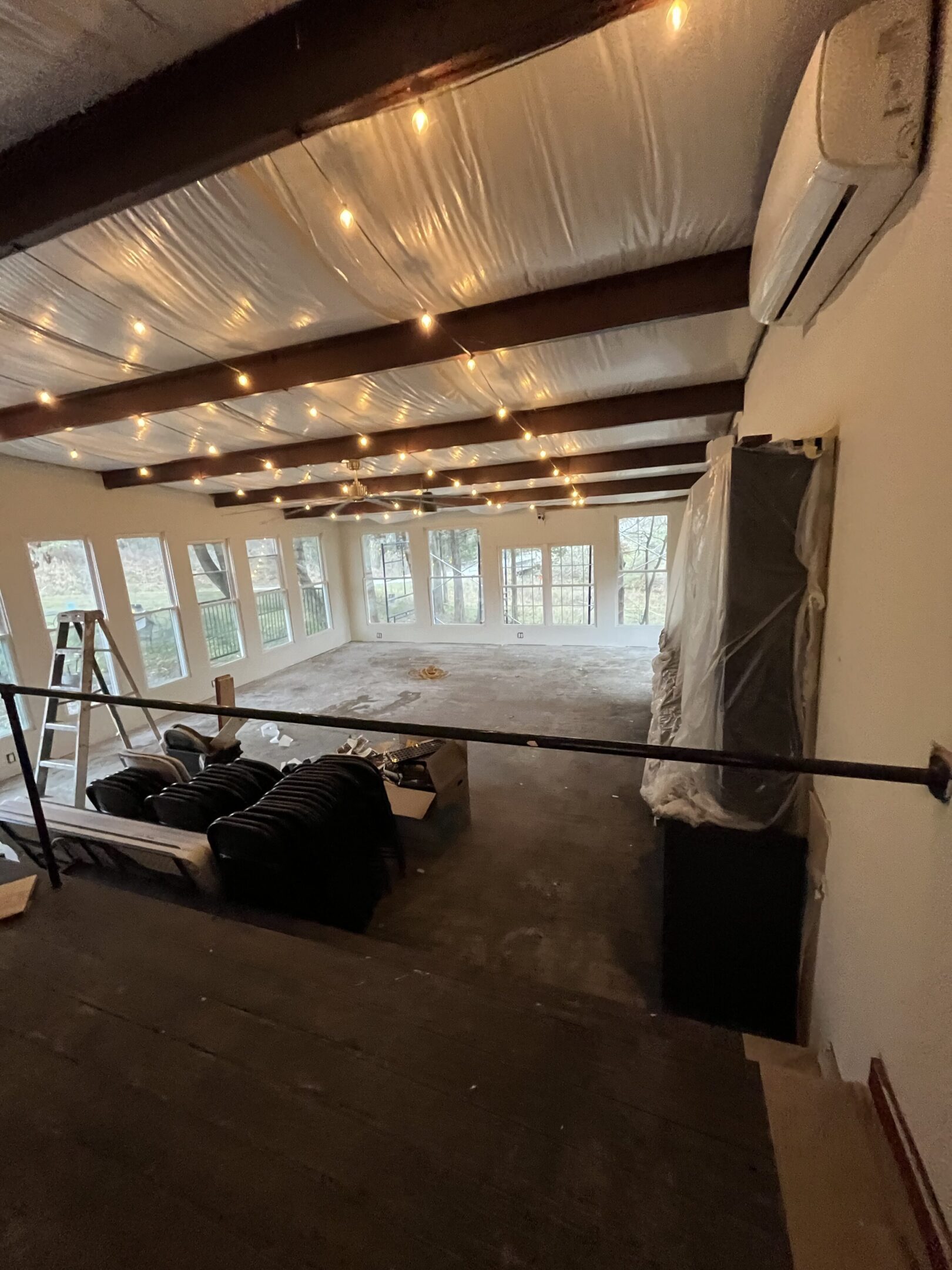 Spacious room with large windows and string lights on the ceiling.