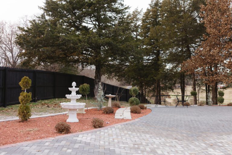 A serene outdoor patio area with a white fountain and trees.