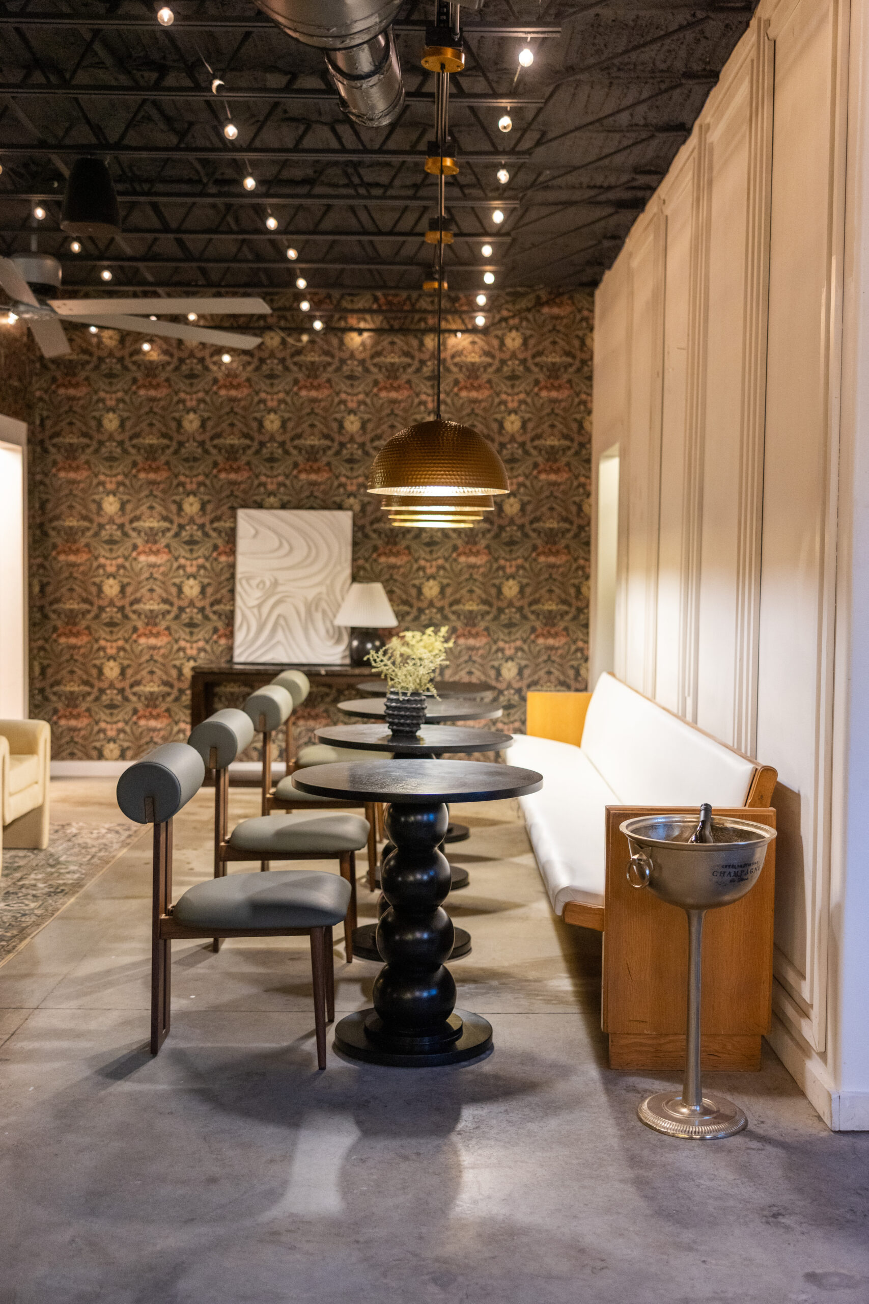 Cozy cafe interior with round tables and cushioned chairs under warm lighting.