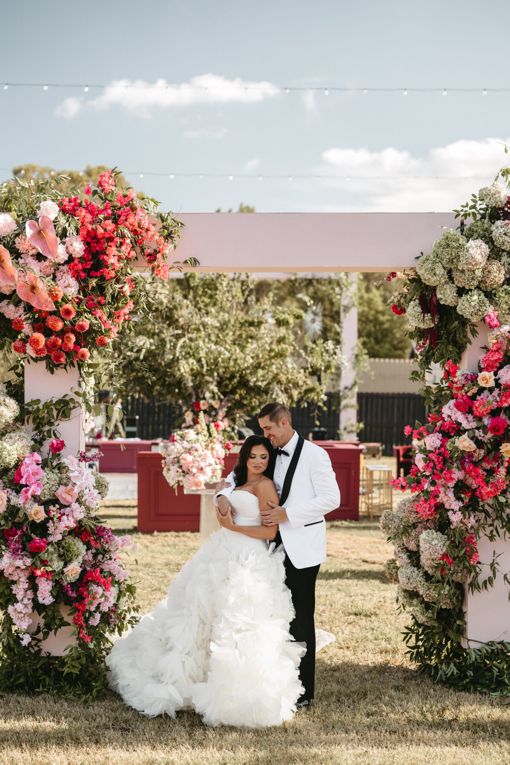 Newlyweds share a joyful moment under a floral arch at their wedding.
