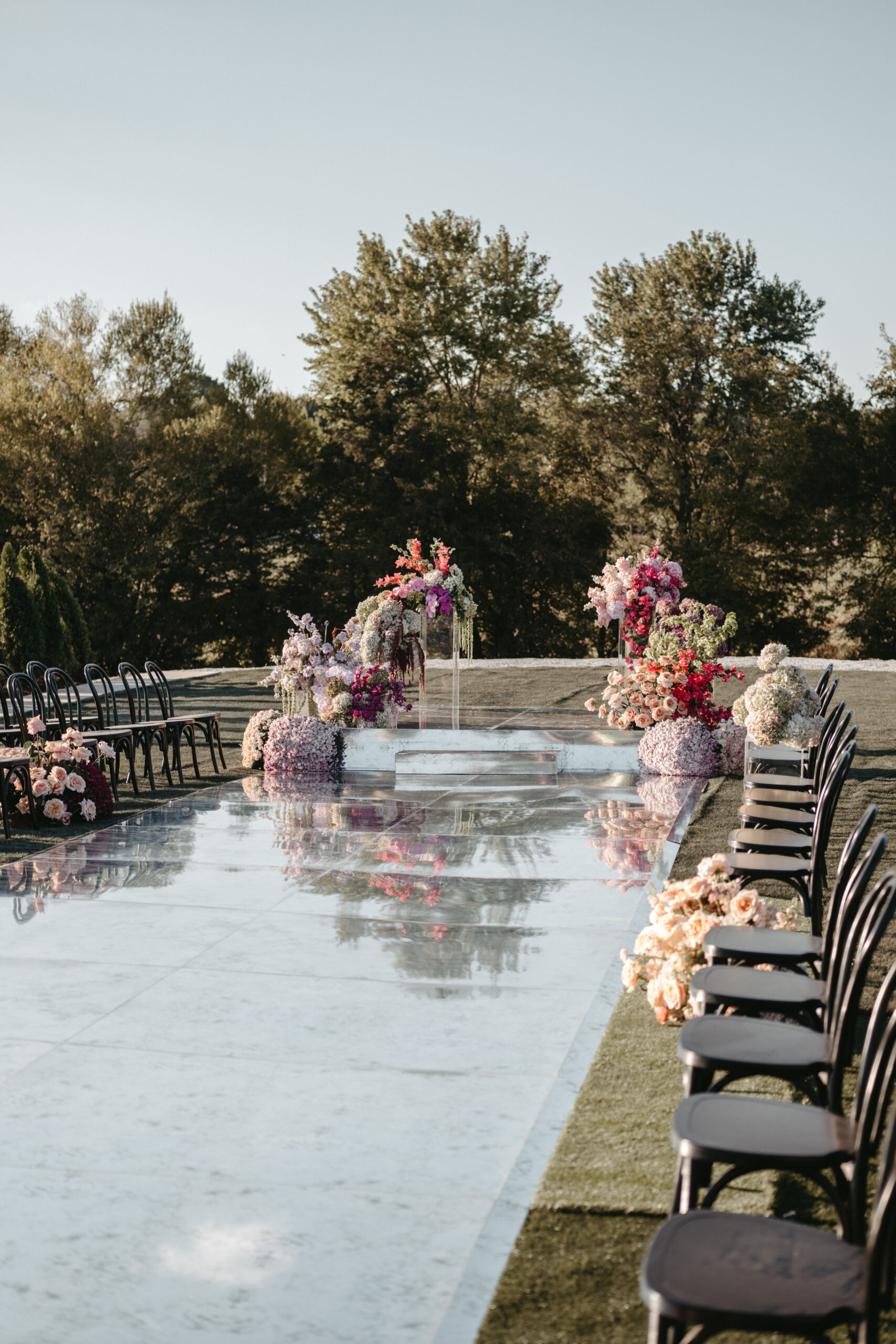 Elegant outdoor wedding aisle decorated with flowers and chairs.