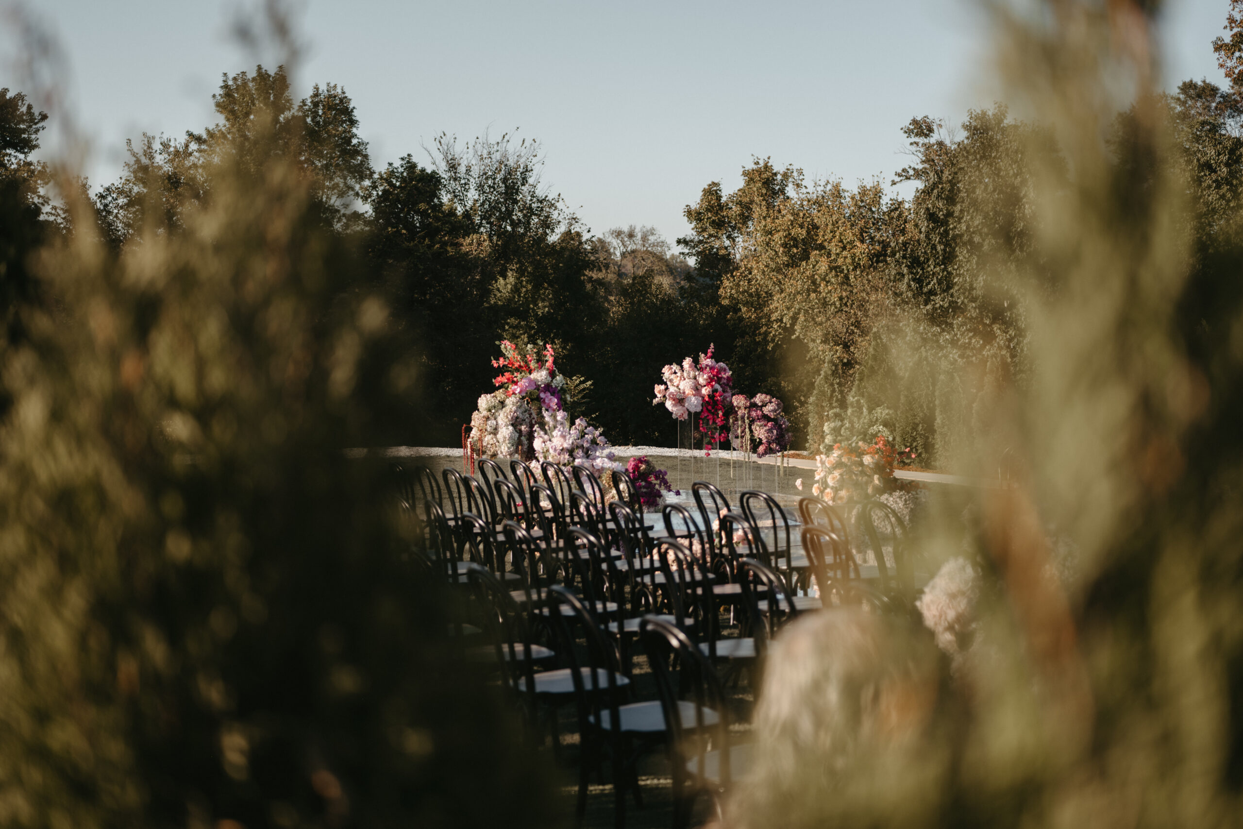Outdoor wedding ceremony setup with floral decorations and wooden chairs.