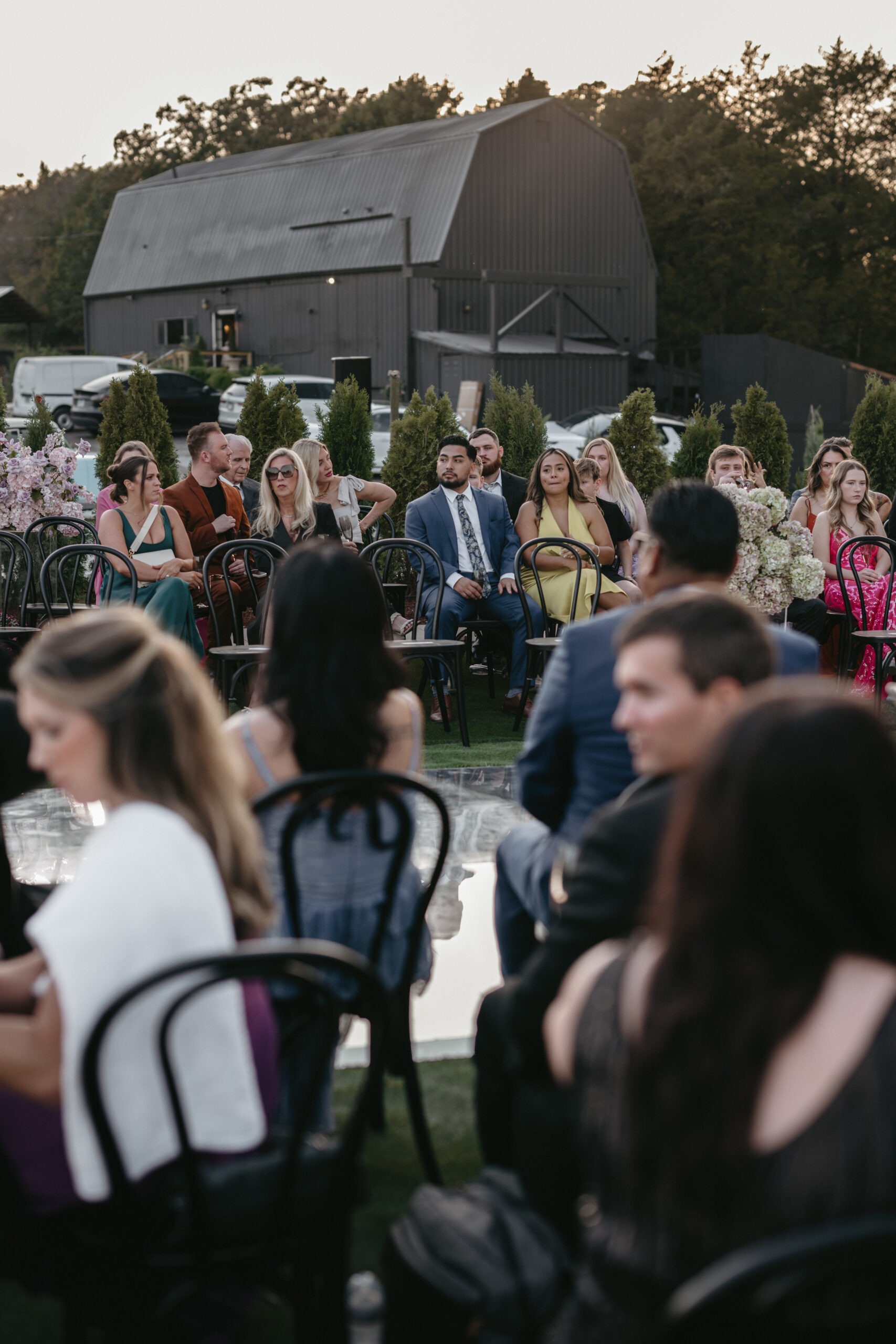 Guests gathered outdoors for a formal event, seated and attentive.