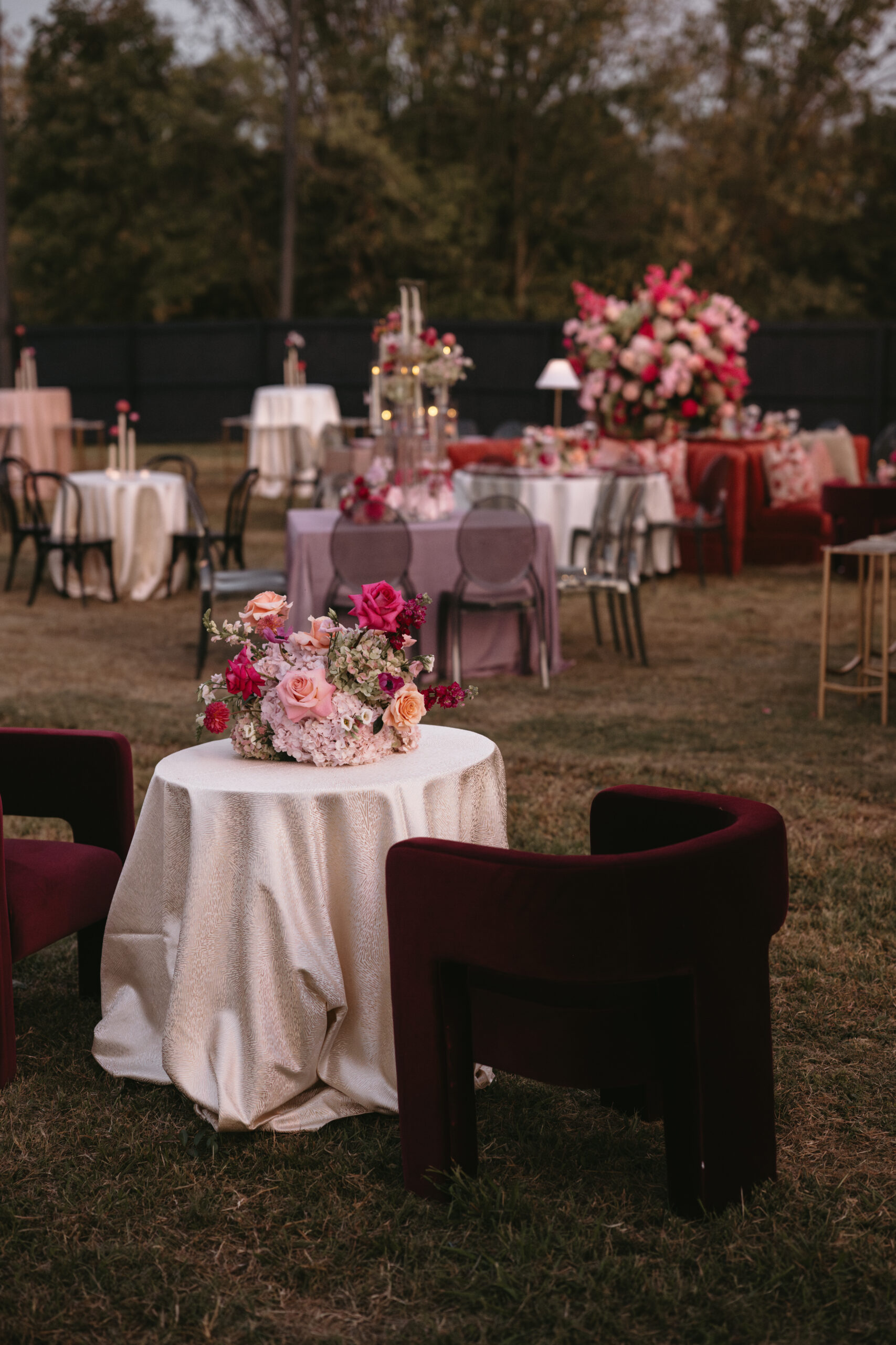 Elegant outdoor event setup with round tables and floral centerpieces.