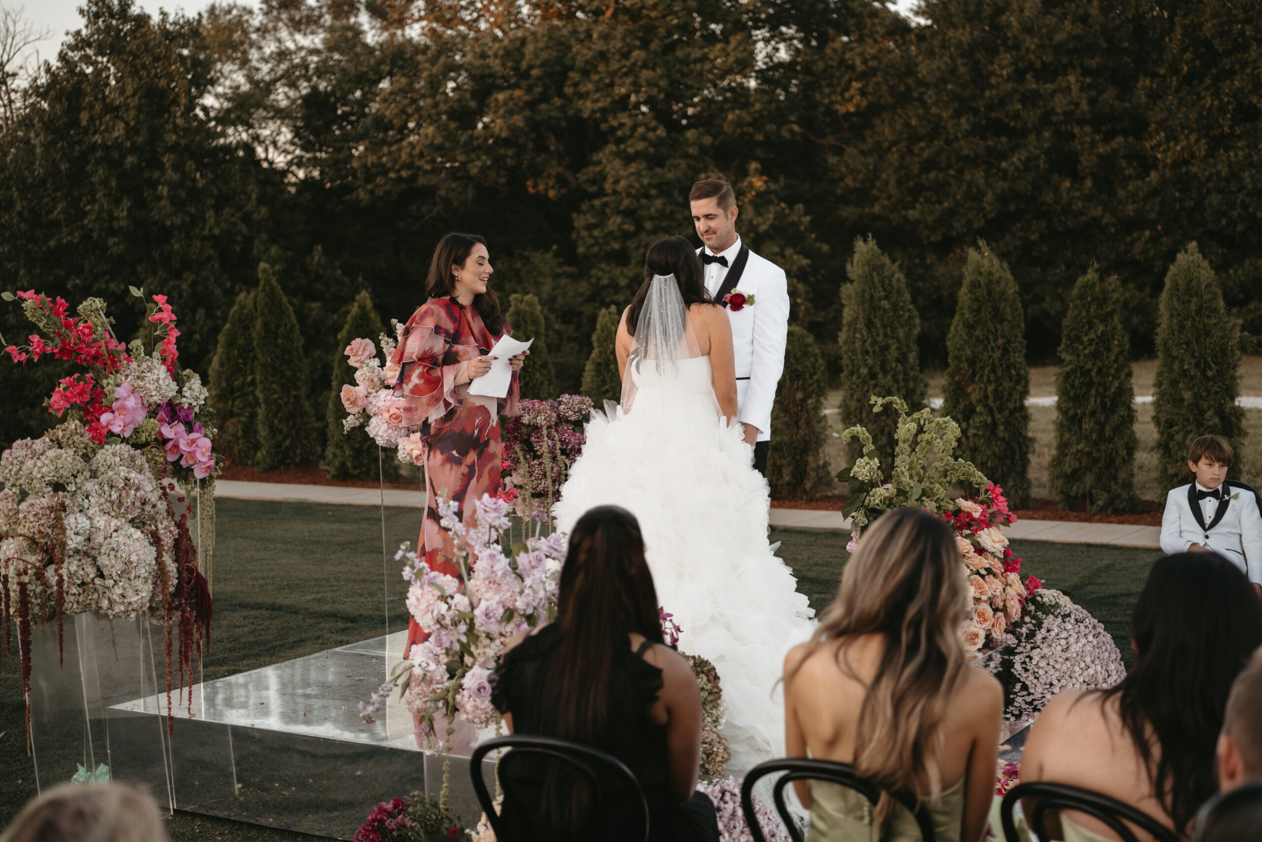 Bride and groom at outdoor wedding ceremony with guests.