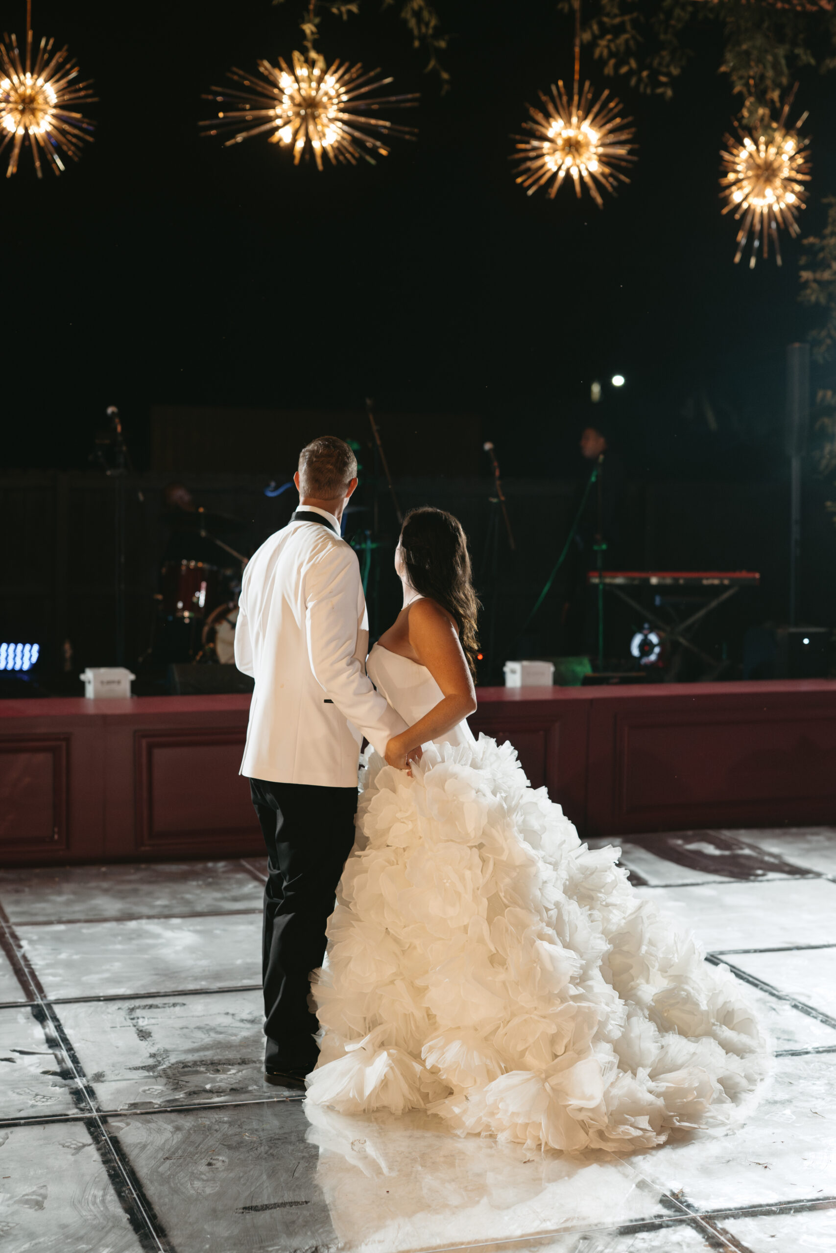 A couple embraces at an elegant nighttime wedding reception.