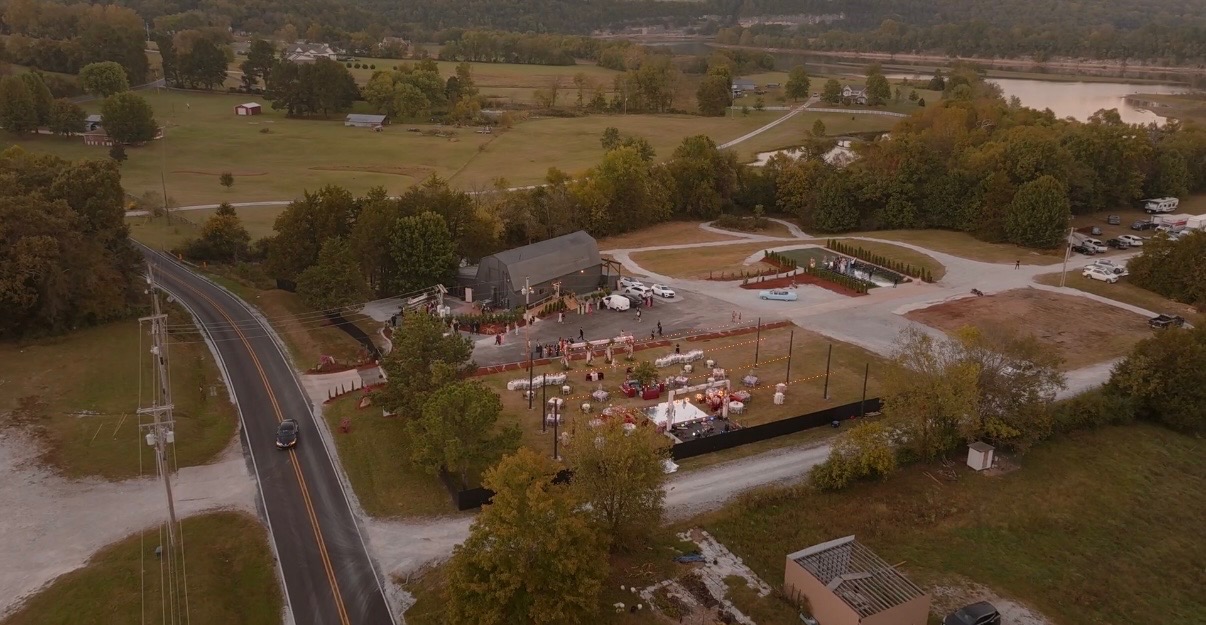 Aerial view of a rural event with tents and people gathered.