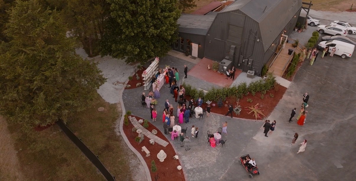 A group gathers outdoors near a barn for an event or ceremony.