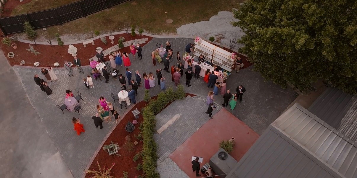 A group of people gathered outdoors near a white truck and garden area.