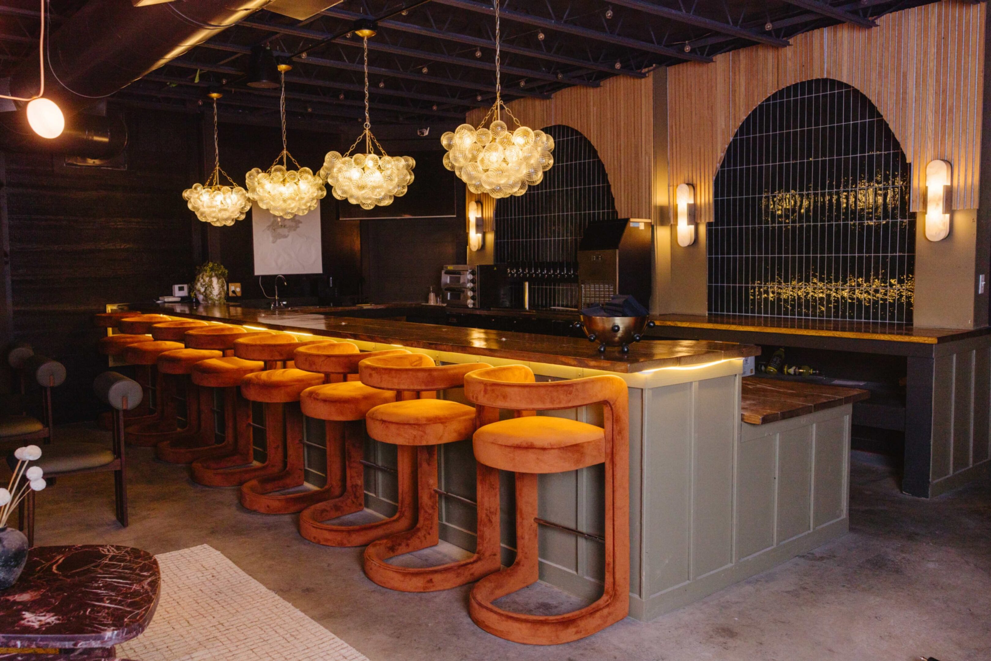 Stylish bar with orange stools and elegant lighting fixtures.